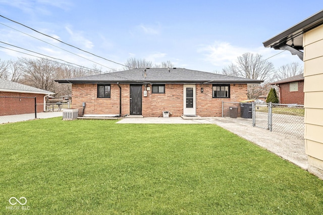 back of property with a gate, a lawn, and brick siding