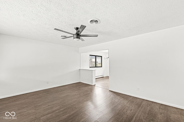 spare room featuring visible vents, baseboard heating, wood finished floors, a textured ceiling, and a ceiling fan