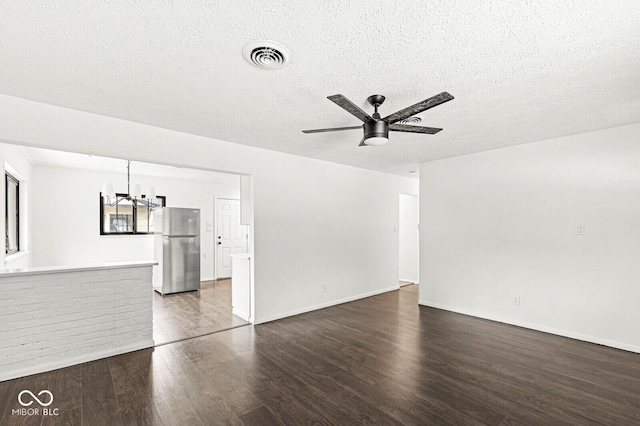 unfurnished room with dark wood-style floors, baseboards, visible vents, a textured ceiling, and ceiling fan with notable chandelier