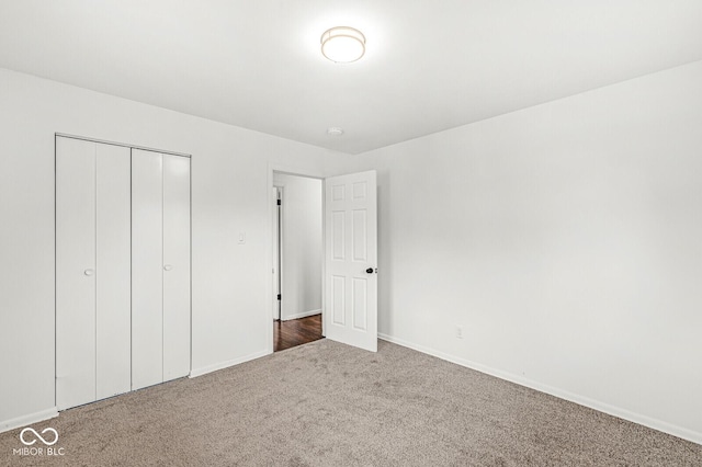 unfurnished bedroom with a closet, carpet flooring, and baseboards