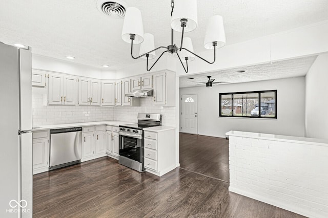 kitchen featuring dark wood-style flooring, light countertops, under cabinet range hood, appliances with stainless steel finishes, and backsplash