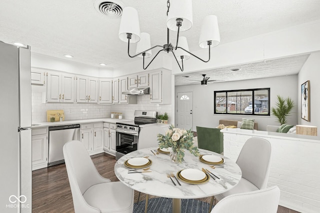 dining space featuring visible vents, ceiling fan with notable chandelier, recessed lighting, dark wood-style floors, and a textured ceiling