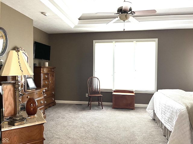 carpeted bedroom featuring ceiling fan, baseboards, and a tray ceiling