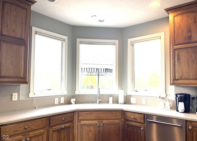 kitchen with recessed lighting, light countertops, brown cabinetry, a sink, and dishwasher