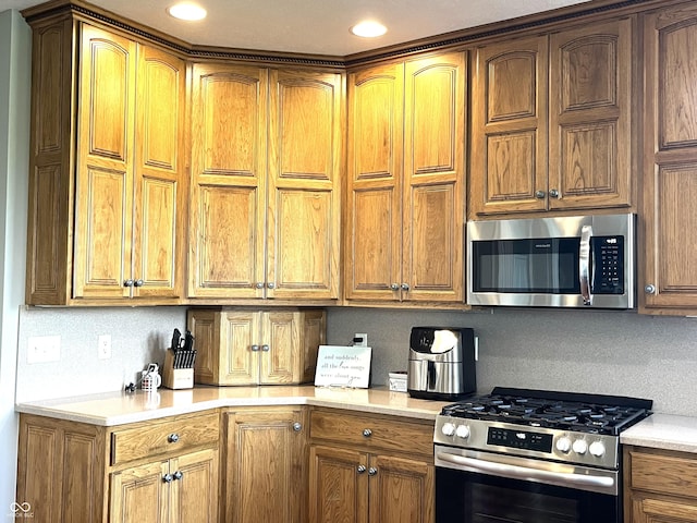 kitchen with brown cabinetry, backsplash, stainless steel appliances, and light countertops