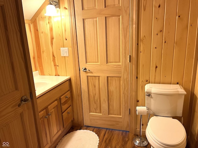 bathroom with vanity, wood finished floors, toilet, and wooden walls