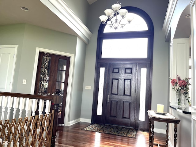 foyer with a chandelier, dark wood-style flooring, a towering ceiling, and baseboards