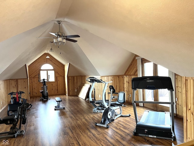 exercise room featuring vaulted ceiling, ceiling fan, wood walls, and wood finished floors