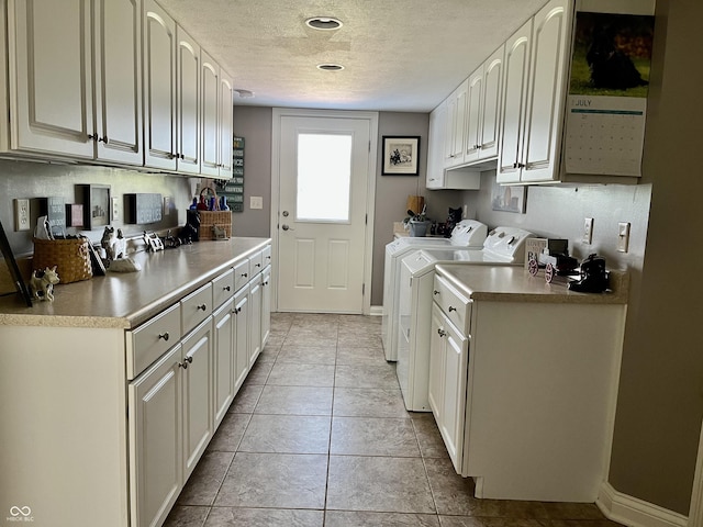 kitchen with a textured ceiling, light tile patterned floors, separate washer and dryer, baseboards, and light countertops