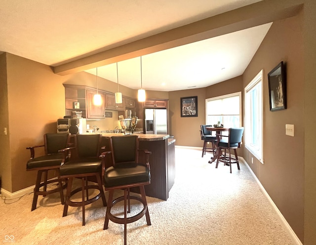 bar featuring baseboards, pendant lighting, light colored carpet, and stainless steel fridge with ice dispenser