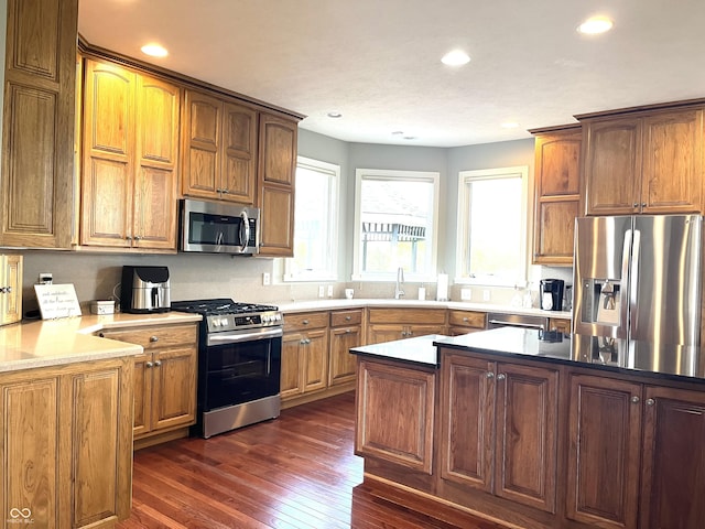 kitchen with dark wood-style flooring, recessed lighting, light countertops, appliances with stainless steel finishes, and a sink