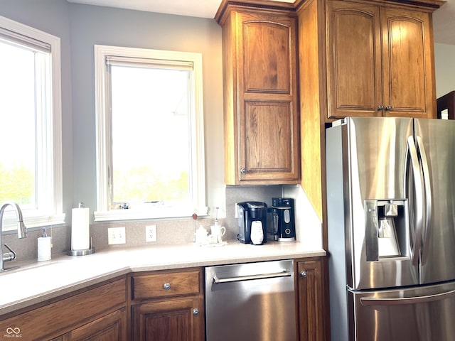 kitchen featuring appliances with stainless steel finishes, brown cabinets, backsplash, and light countertops