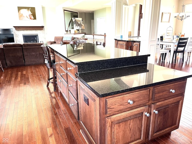 kitchen featuring brown cabinets, a glass covered fireplace, dark wood-type flooring, and a center island