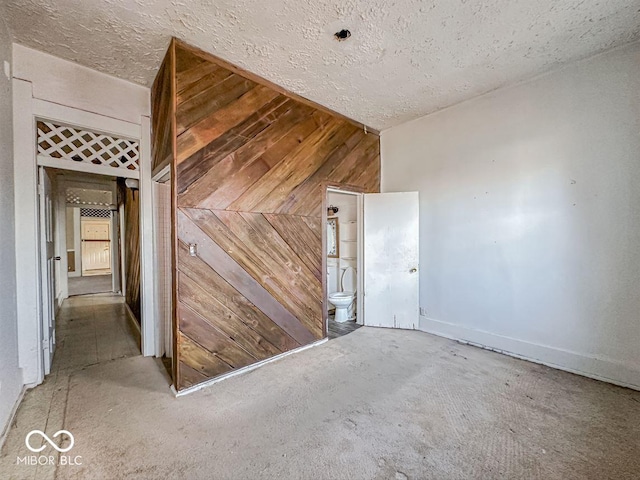 spare room featuring wood walls and a textured ceiling