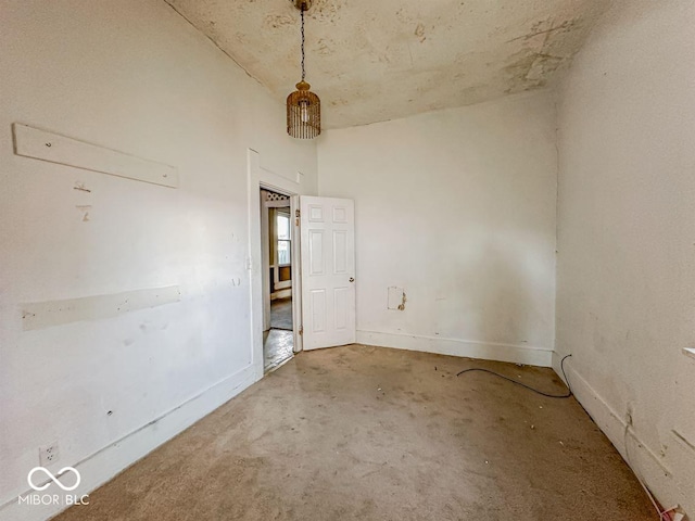 unfurnished room featuring baseboards and a towering ceiling