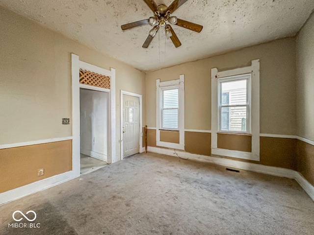 spare room with visible vents, a textured ceiling, carpet, baseboards, and ceiling fan