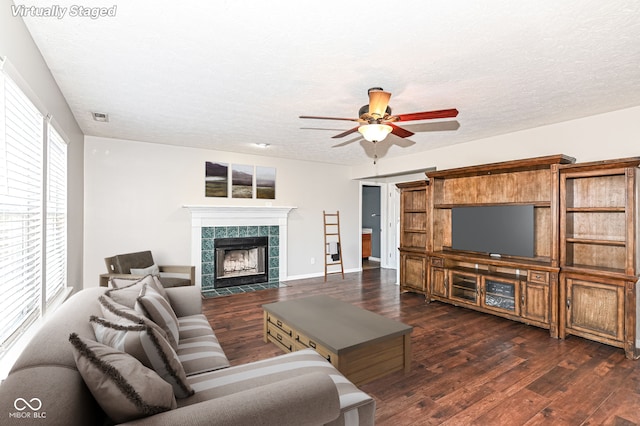 living room with wood finished floors, a textured ceiling, ceiling fan, and a fireplace