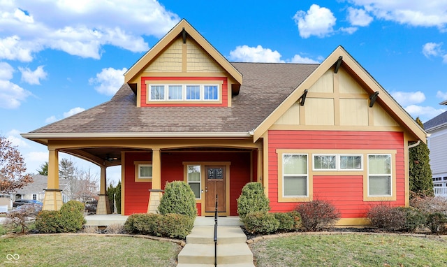 view of front facade featuring a front yard, covered porch, and roof with shingles