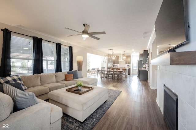 living area with a tiled fireplace, wood finished floors, and a ceiling fan