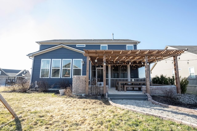 back of house with a lawn, a pergola, and fence