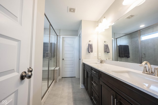 bathroom with double vanity, a stall shower, visible vents, and a sink