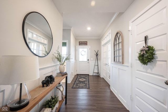 doorway to outside featuring dark wood-style floors, a wainscoted wall, recessed lighting, crown molding, and a decorative wall