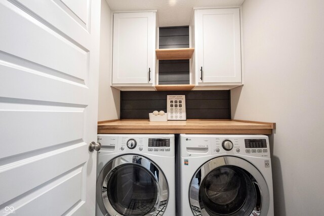 washroom with cabinet space and washing machine and clothes dryer