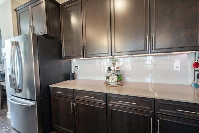 kitchen with decorative backsplash, dark brown cabinets, stainless steel fridge with ice dispenser, and light countertops