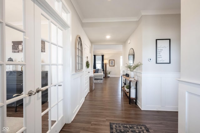 hall featuring crown molding, a decorative wall, french doors, and dark wood-type flooring