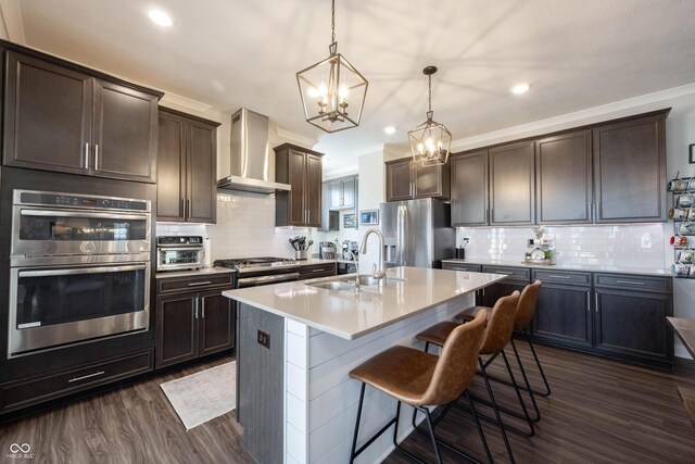 kitchen with dark brown cabinetry, appliances with stainless steel finishes, wall chimney exhaust hood, and a sink