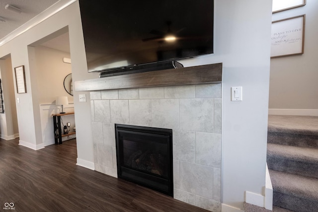 details with a tiled fireplace, wood finished floors, and baseboards