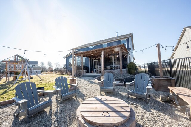 rear view of house with a patio, a playground, fence, and a lawn