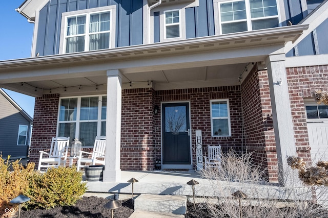 entrance to property featuring brick siding, covered porch, and board and batten siding