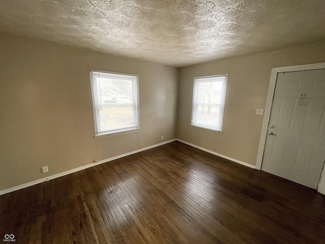 spare room featuring baseboards, a textured ceiling, and dark wood-style floors