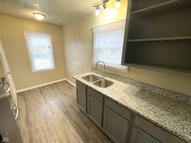 kitchen featuring wood finished floors, open shelves, a sink, gray cabinetry, and a textured ceiling