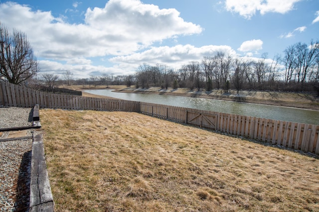 view of yard with a water view and a fenced backyard