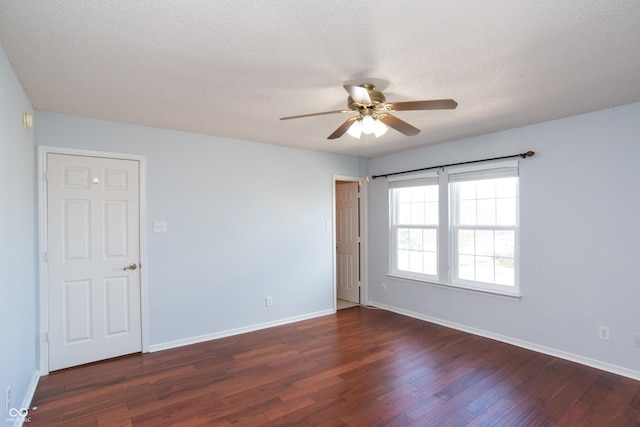 empty room featuring a textured ceiling, dark wood finished floors, a ceiling fan, and baseboards