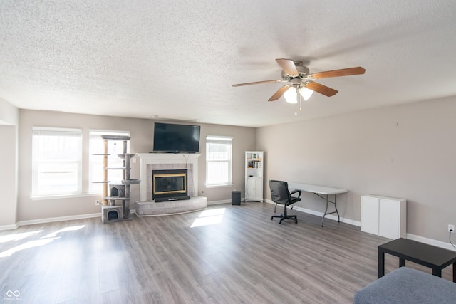 office with a fireplace, a textured ceiling, baseboards, and wood finished floors