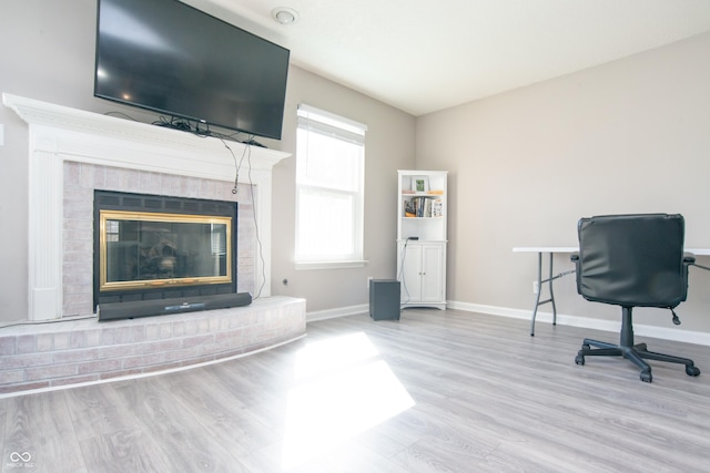 office area featuring a fireplace, baseboards, and wood finished floors