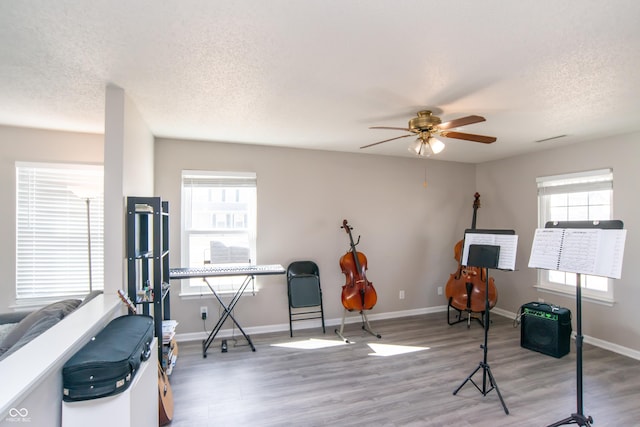 workout room featuring a textured ceiling, wood finished floors, and baseboards