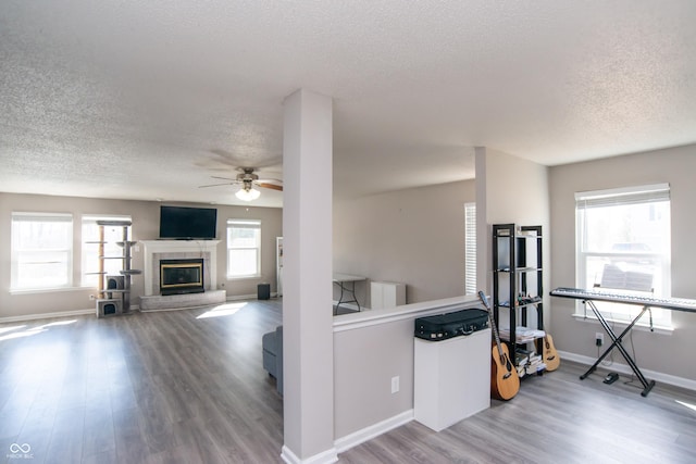 kitchen with ceiling fan, a textured ceiling, a tile fireplace, wood finished floors, and baseboards