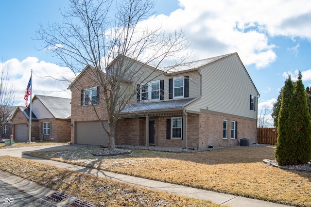 traditional home with an attached garage, brick siding, fence, driveway, and a front lawn