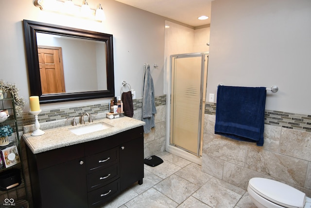 bathroom featuring toilet, recessed lighting, vanity, tile walls, and a shower stall