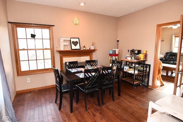 dining space featuring a fireplace, baseboards, and hardwood / wood-style floors