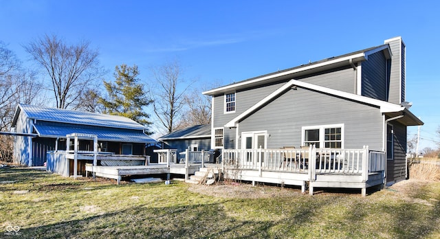 rear view of property featuring a chimney, a deck, and a lawn