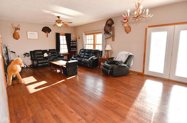 living room featuring visible vents, ceiling fan with notable chandelier, and hardwood / wood-style flooring