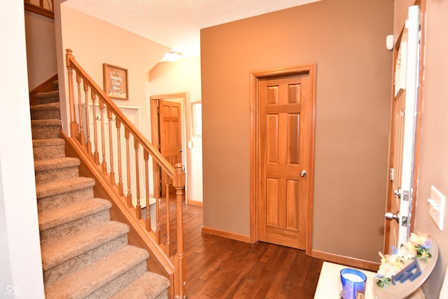 staircase with a textured ceiling, hardwood / wood-style flooring, and baseboards