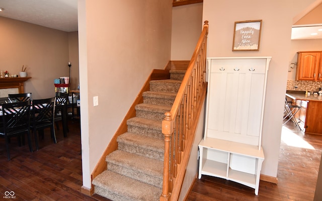 stairs with a fireplace, hardwood / wood-style flooring, and baseboards