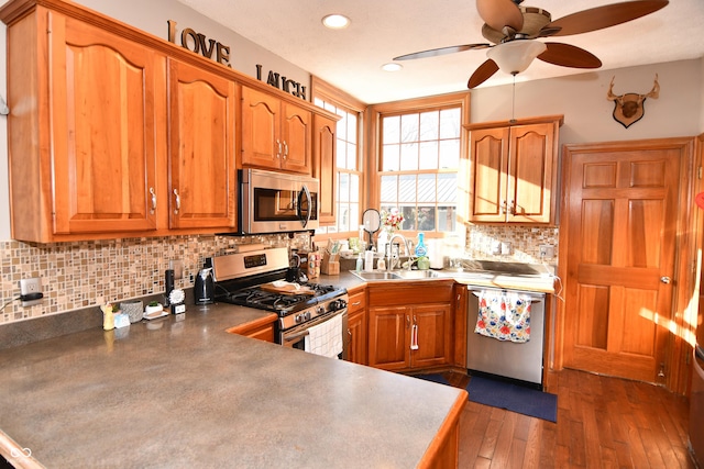 kitchen with stainless steel appliances, brown cabinets, a sink, and dark wood-style floors