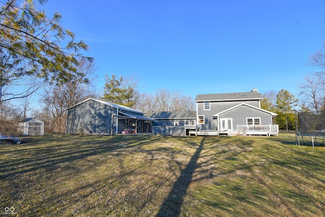 back of property with a trampoline, a yard, a deck, a shed, and an outdoor structure